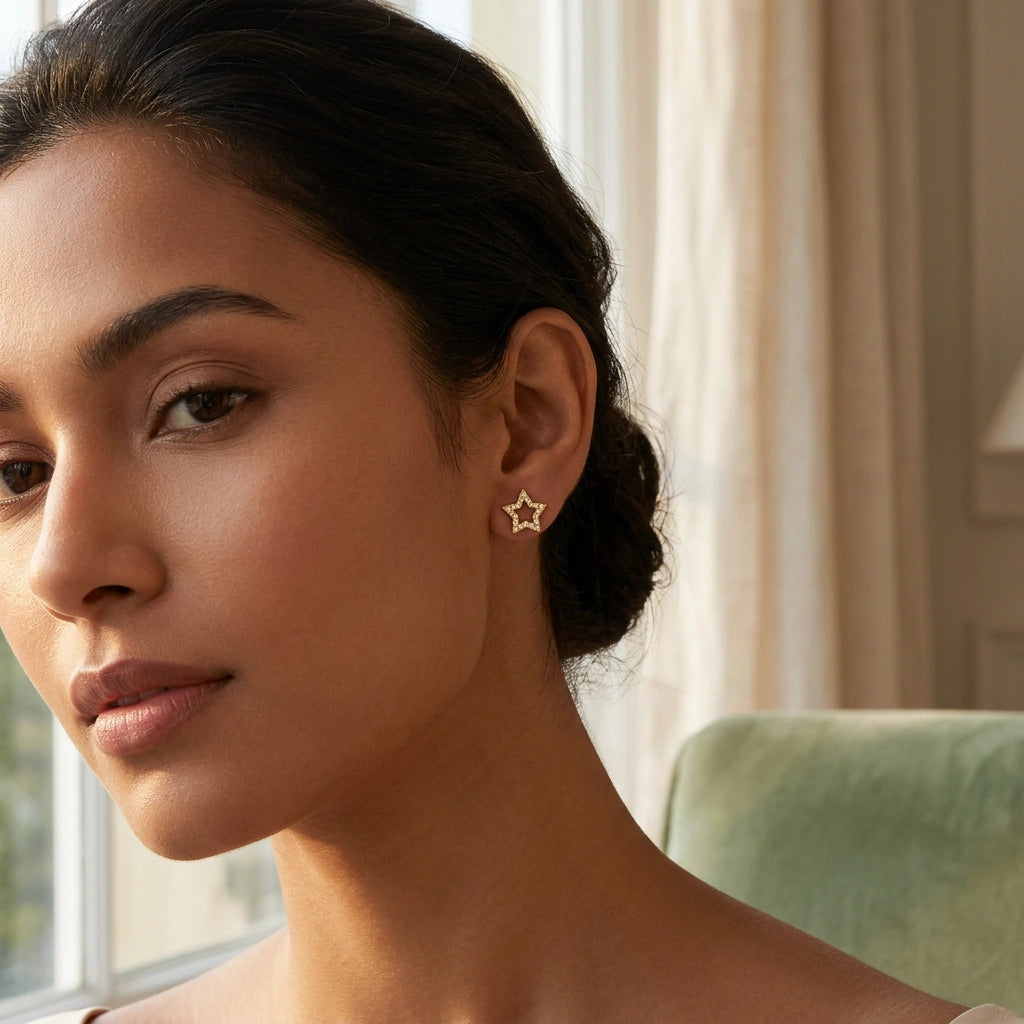 woman wearing a star-shaped 18k gold plated earring indoors with a neutral background