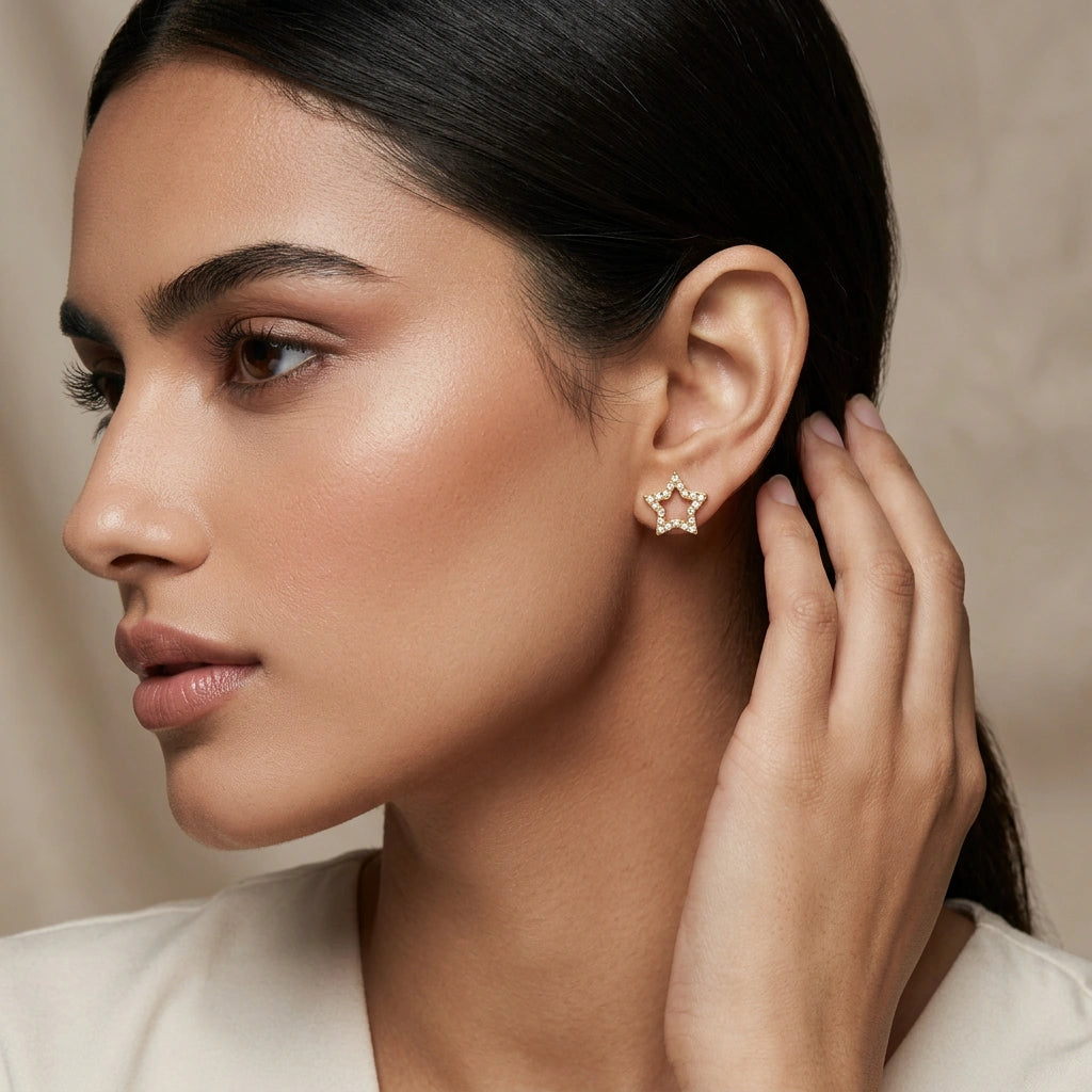 close-up of a woman wearing a star-shaped 18k gold plated earring with a neutral background