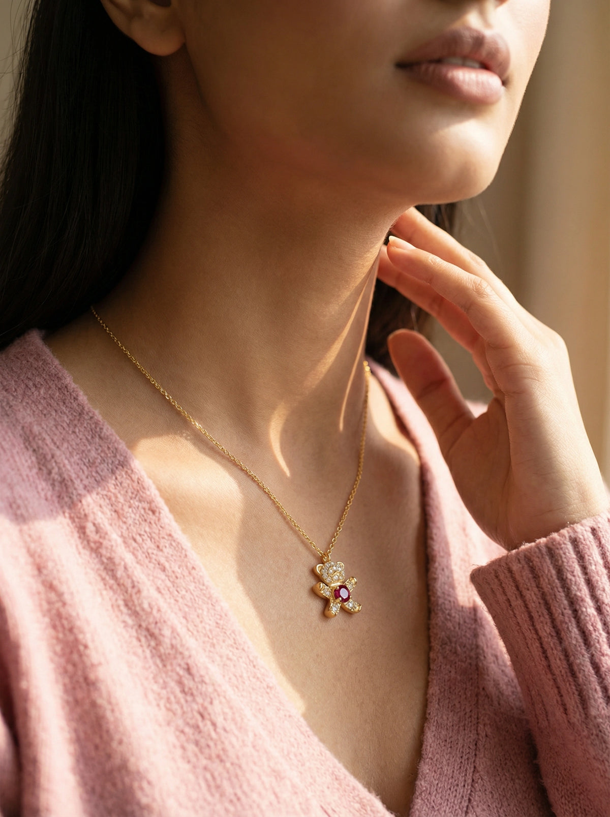 woman wearing a 18k  gold plated necklace with a pendant, touching her hair.