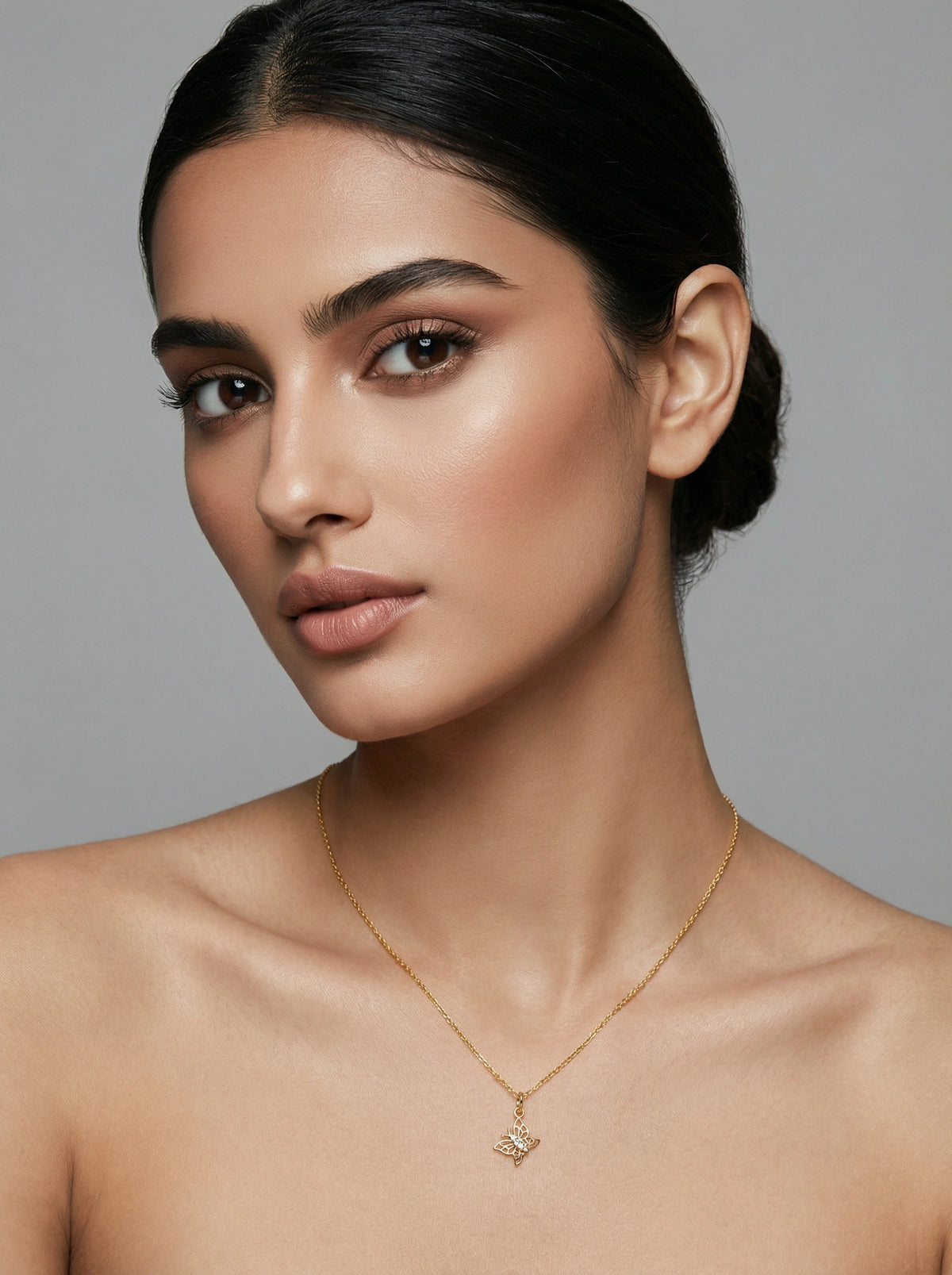 woman wearing a 18k gold plated necklace against a gray background