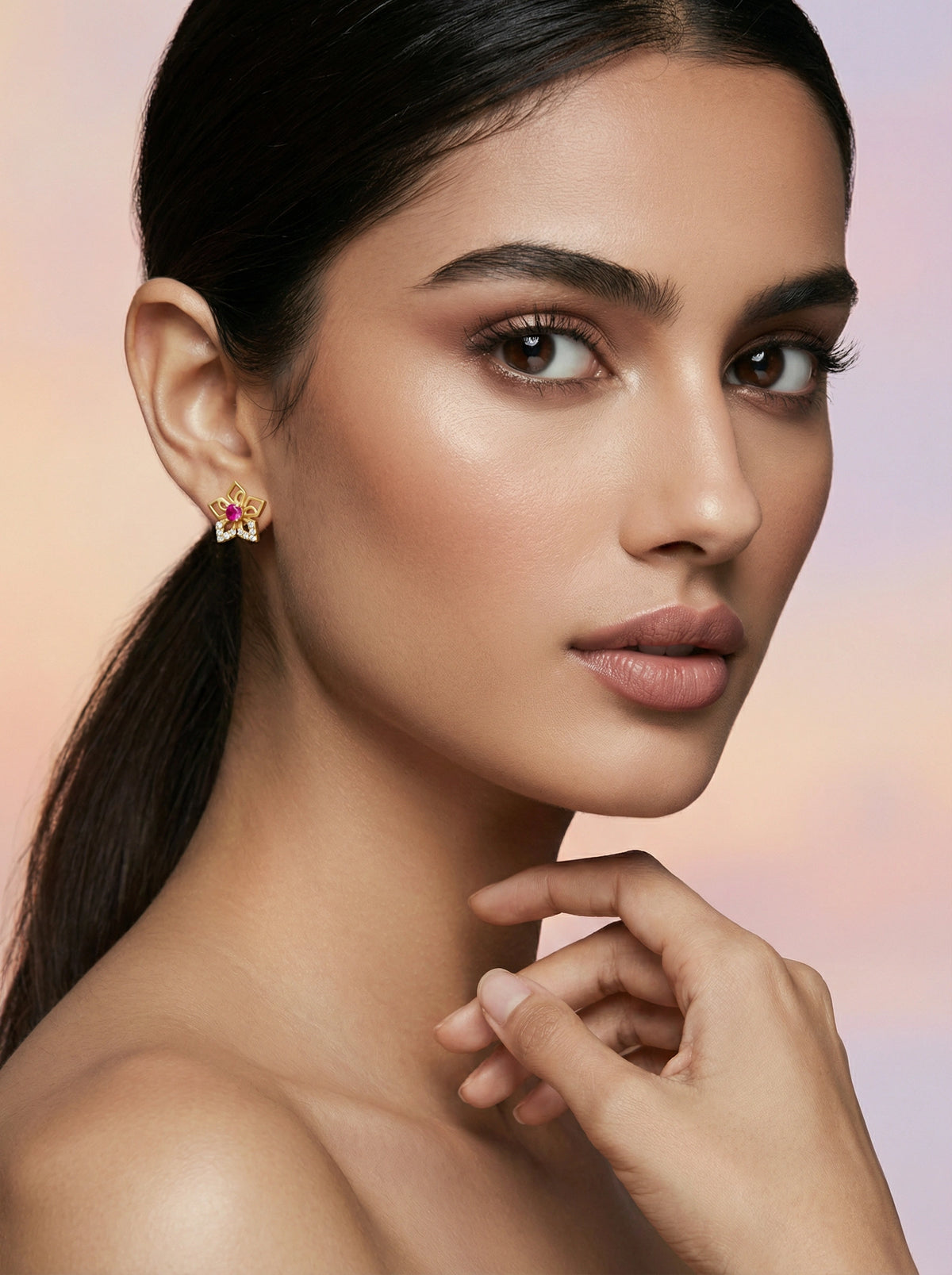 woman wearing a 18k  gold plated earring with a pink gemstone against a soft background