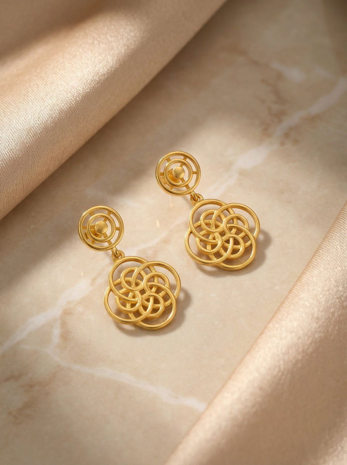 18k gold plated earrings on a beige fabric background