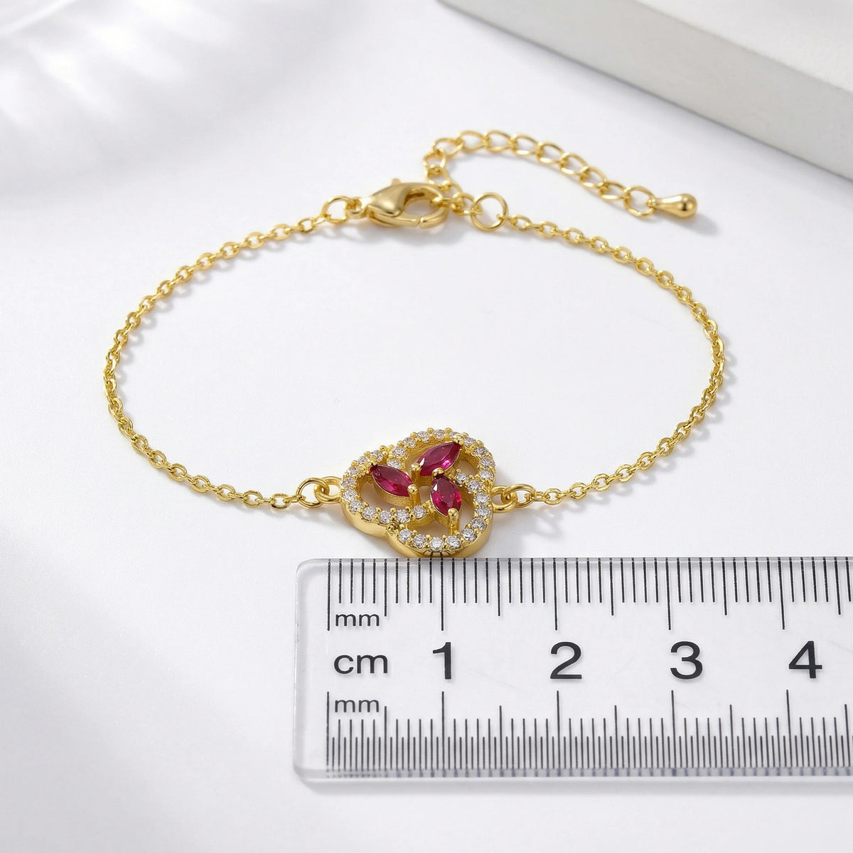 18k gold plated bracelet with gemstones next to a ruler on a white background