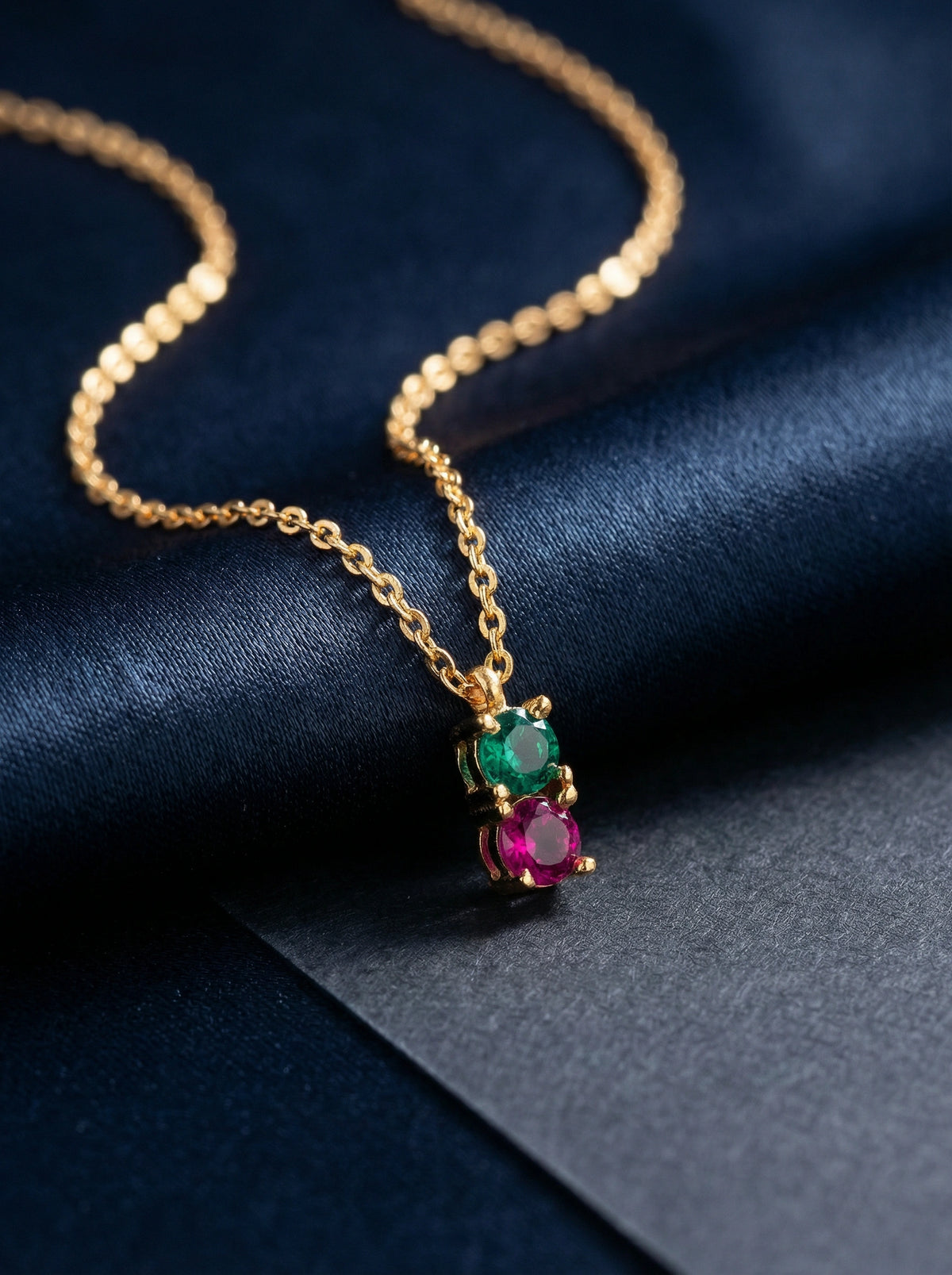18k gold plated necklace with gemstone pendant on a dark blue fabric background