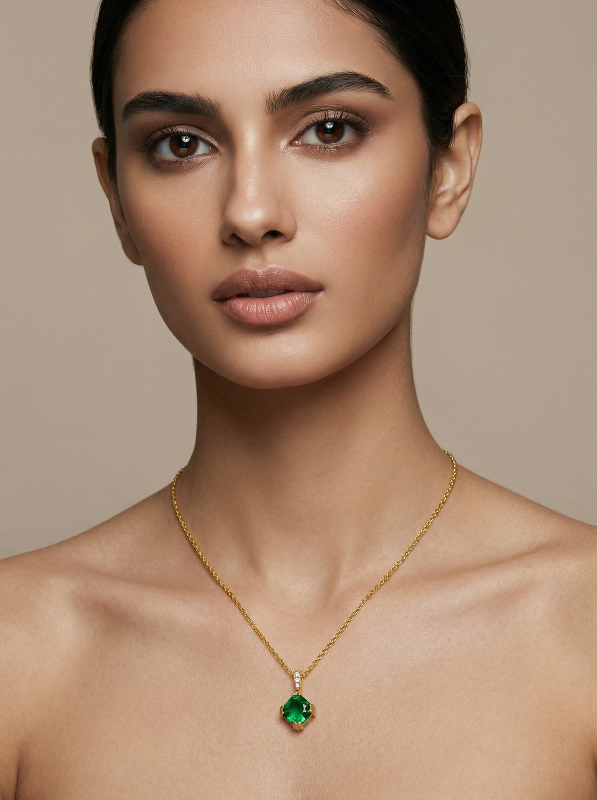 woman wearing a 18k gold plated necklace with a green pendant against a beige background