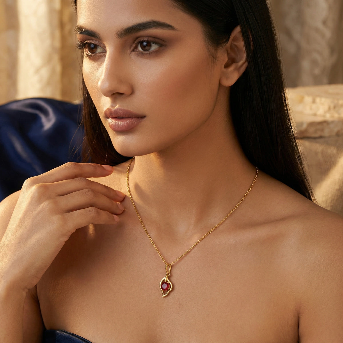 woman wearing a 18k gold plated necklace with a red gemstone pendant against a neutral background