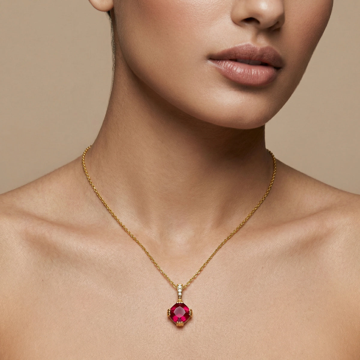 close-up of a person wearing a 18k gold plated necklace with a red gemstone pendant on a beige background