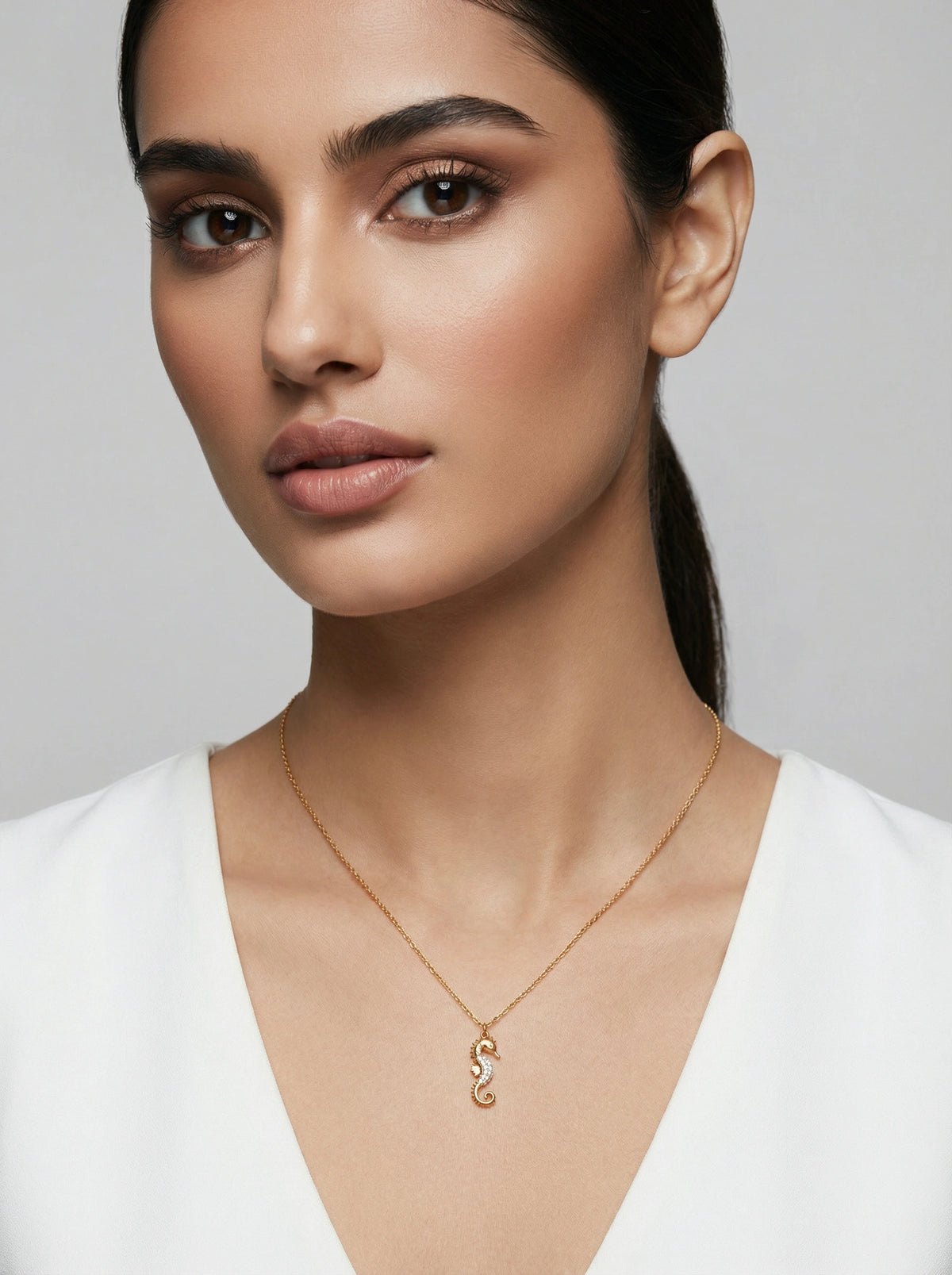 woman wearing a 18k gold plated necklace with a unique pendant against a neutral background