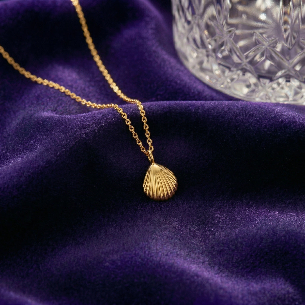 18k gold plated necklace with a shell pendant on a purple fabric background