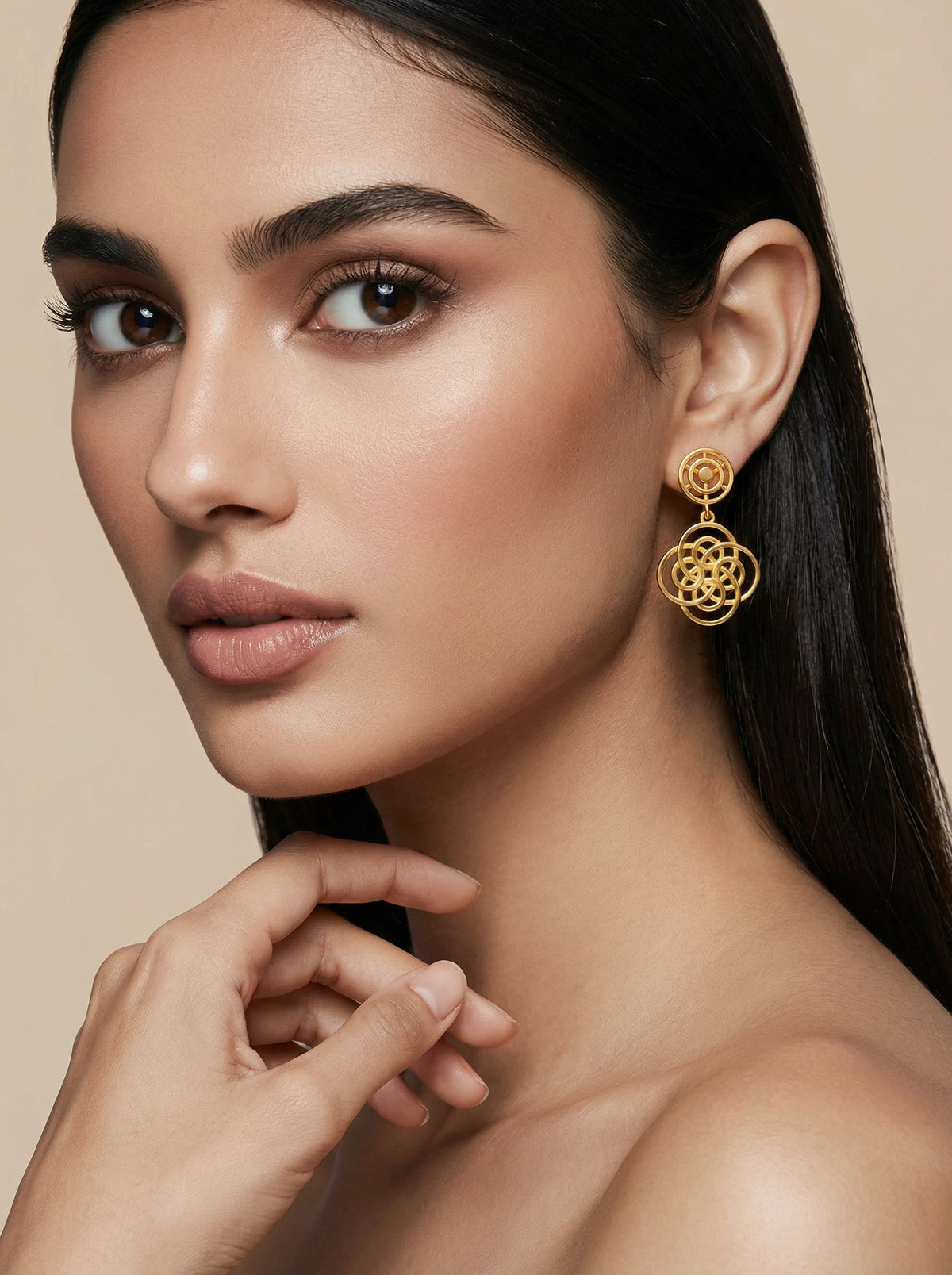 woman wearing 18k gold plated earrings with a neutral background
