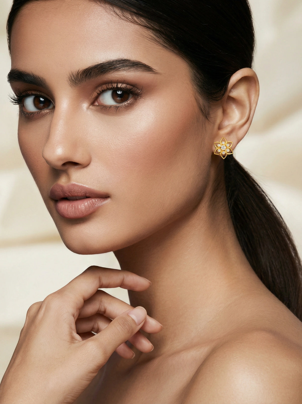 close-up of a woman wearing a 18k gold plated earring with a neutral background