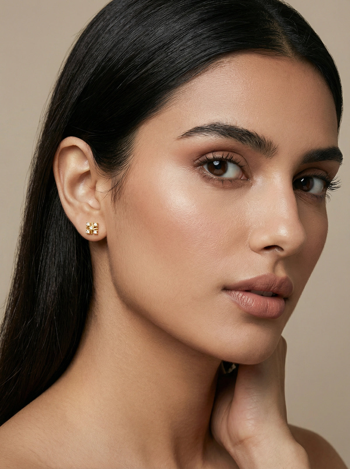 close-up of a woman wearing 18k gold plated earrings with a neutral background