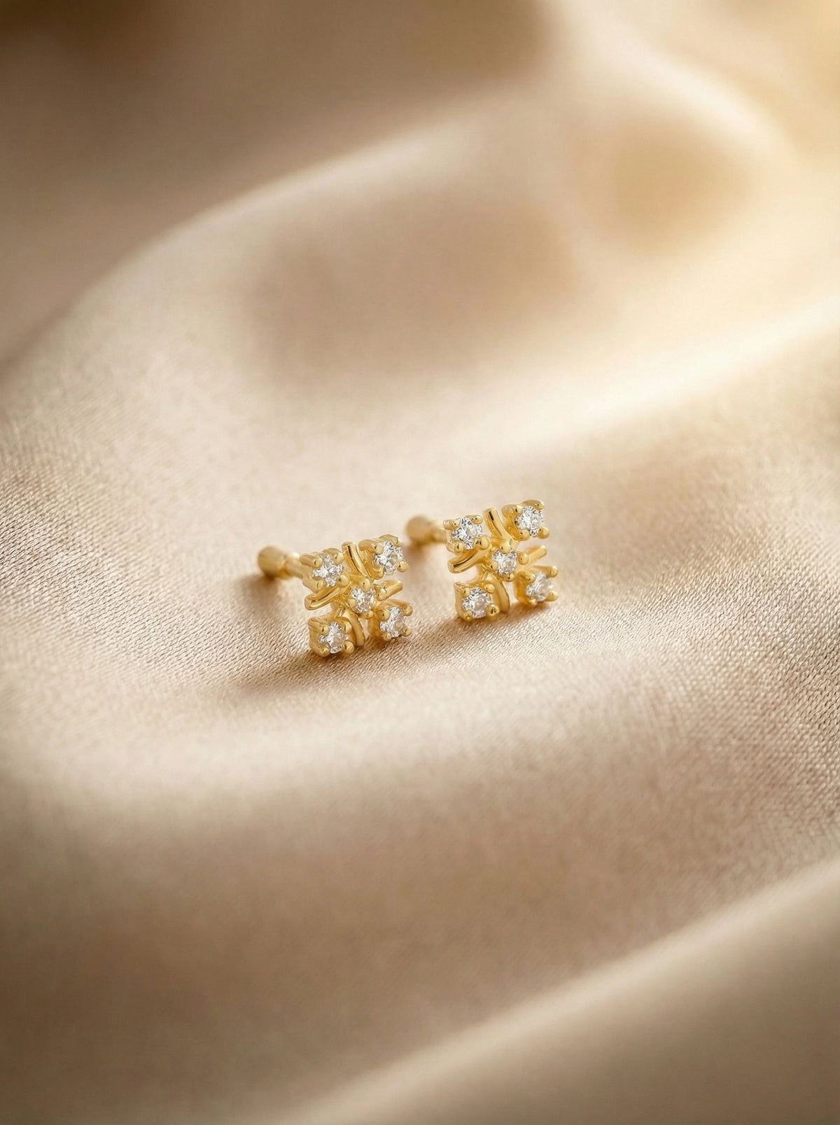 18k gold plated earrings with gemstones on a beige fabric background