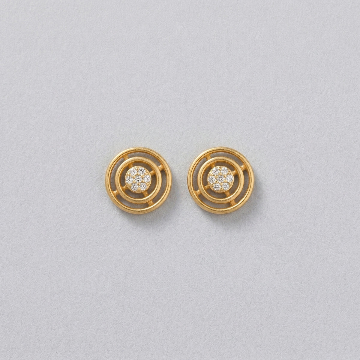 18k gold plated earrings with circular design on a light gray background