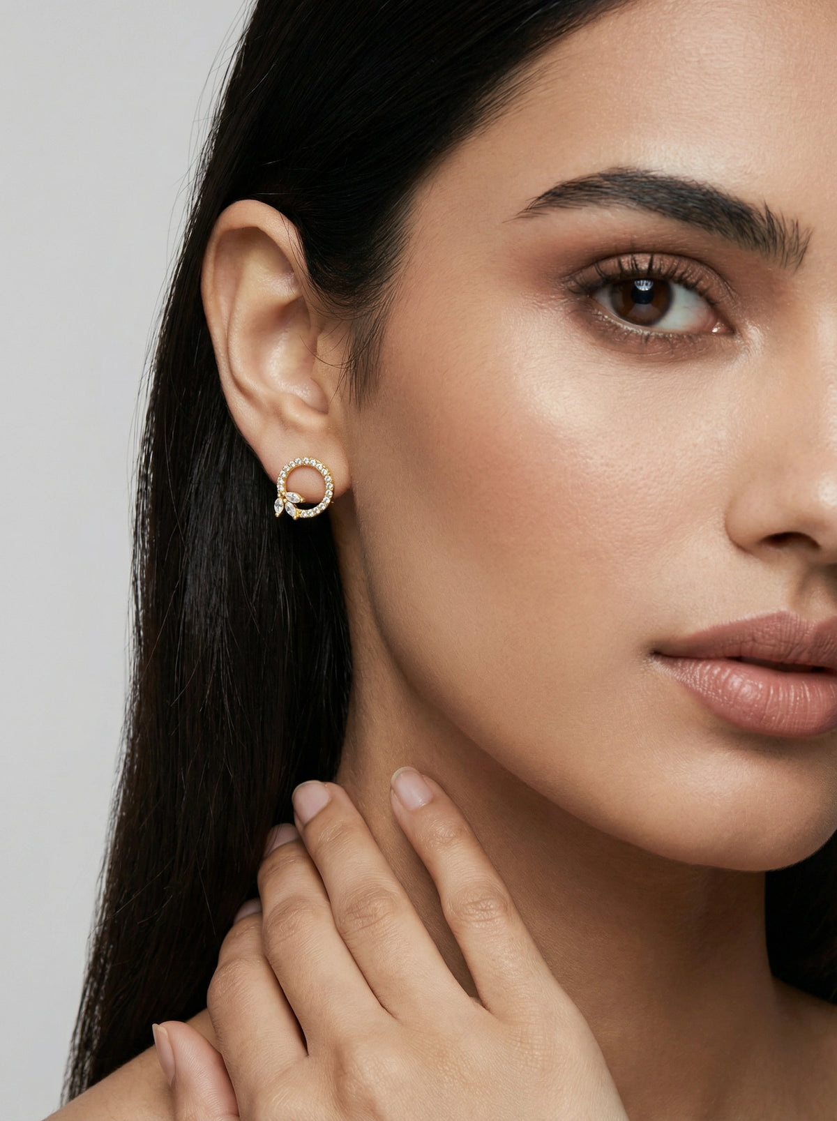 close-up of a woman wearing a 18k  gold plated earring with a gray background