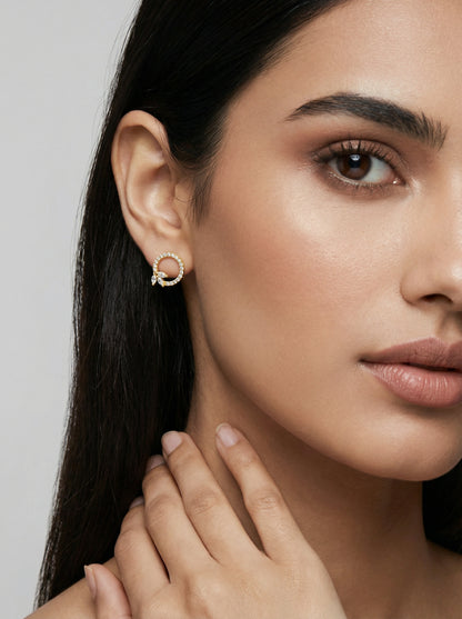 Close-up of a woman wearing a 18k  gold plated earring with a gray background