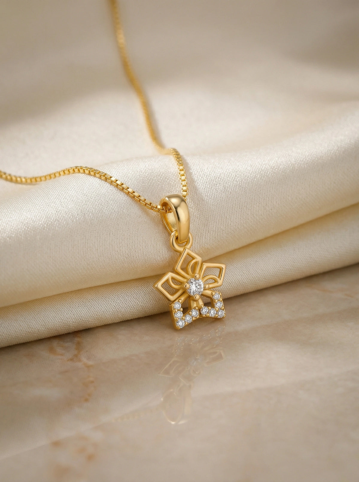 18k gold plated necklace with a floral pendant on a beige fabric background