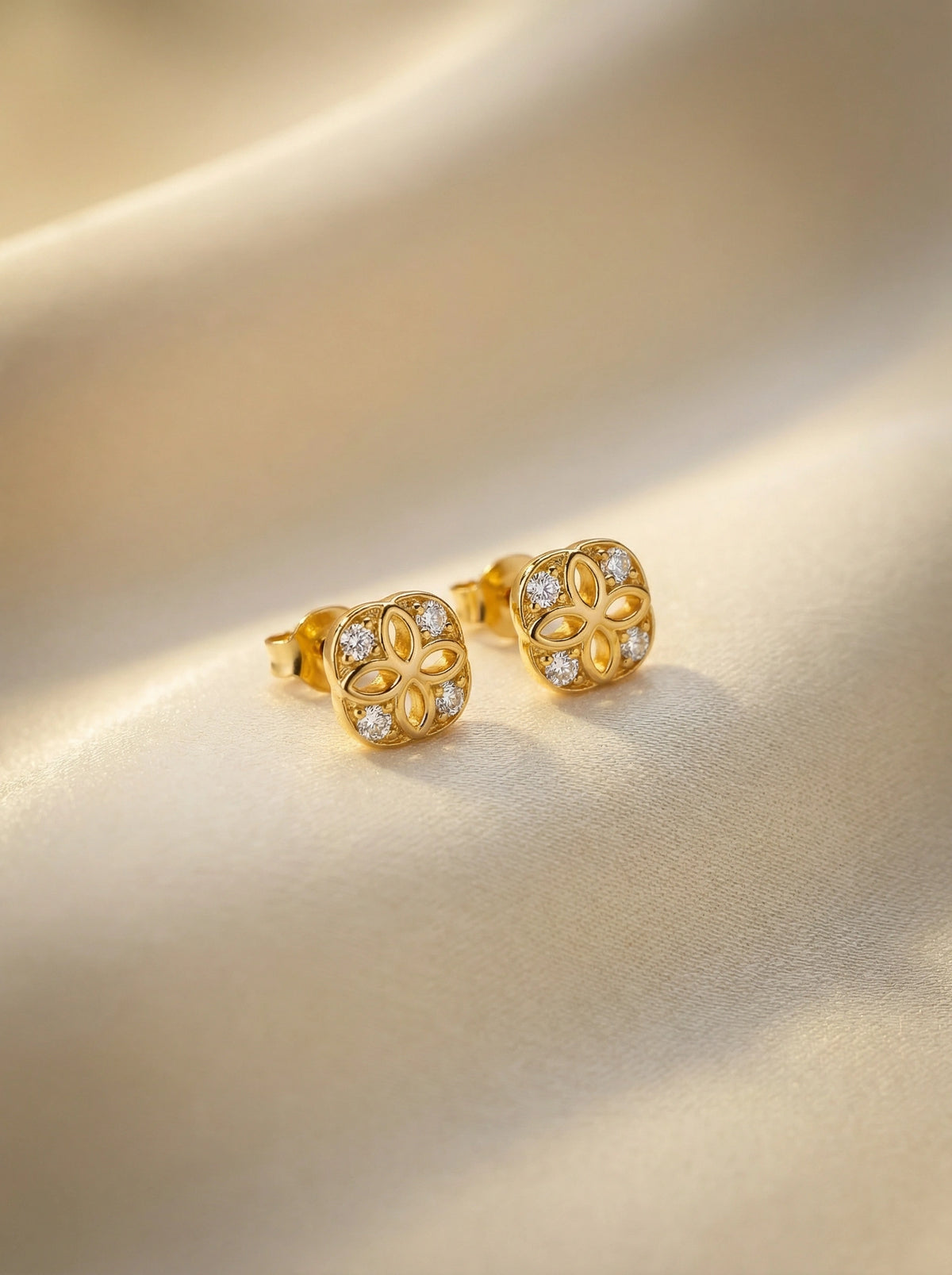18k Gold plated earrings with diamond accents on a beige background