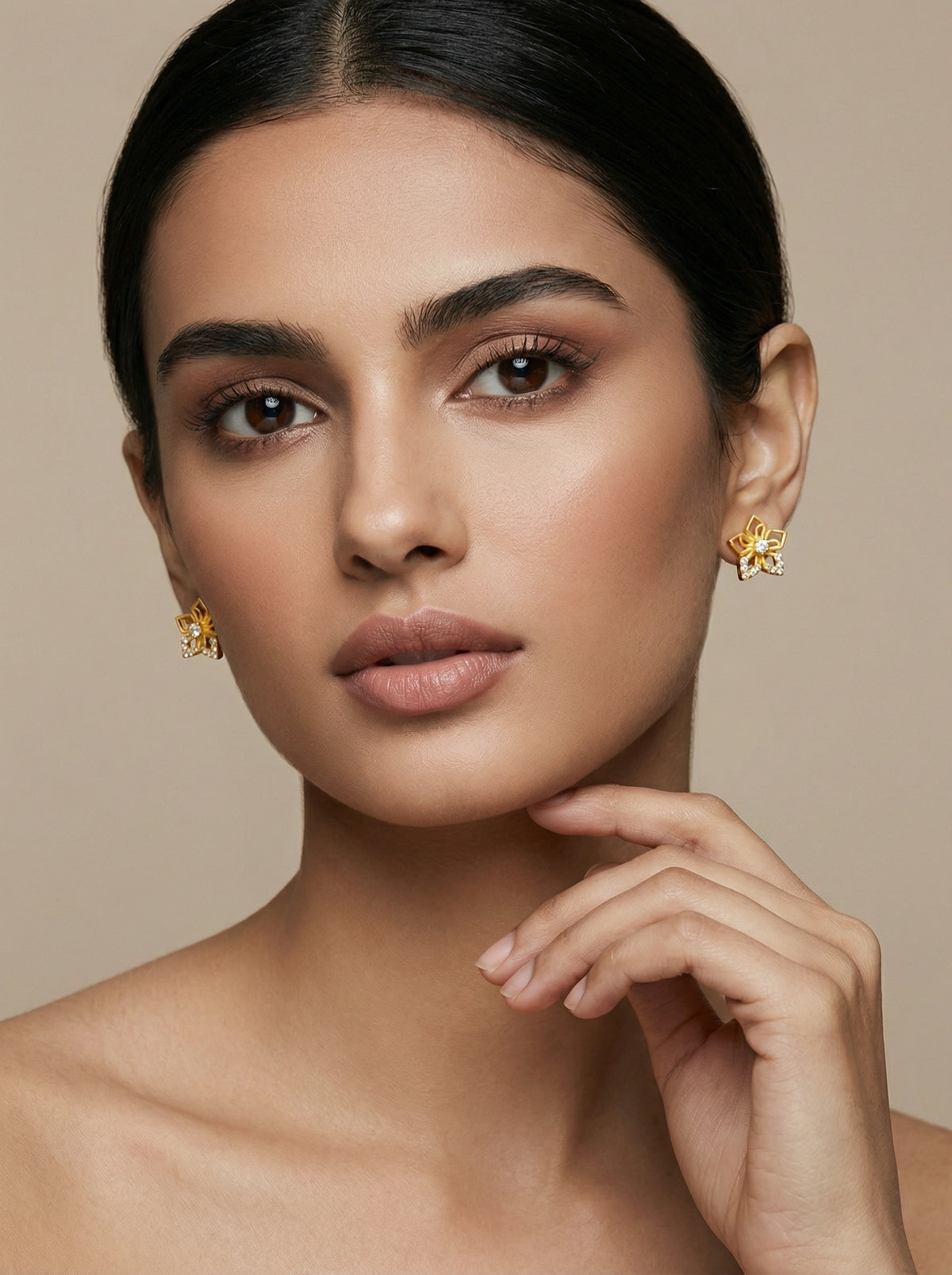 woman wearing 18k gold plated earrings against a beige background