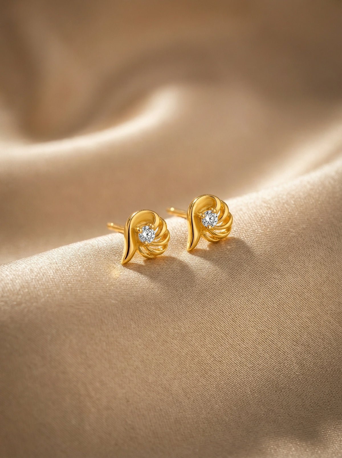 18k gold plated earrings with diamond accents on a beige fabric background