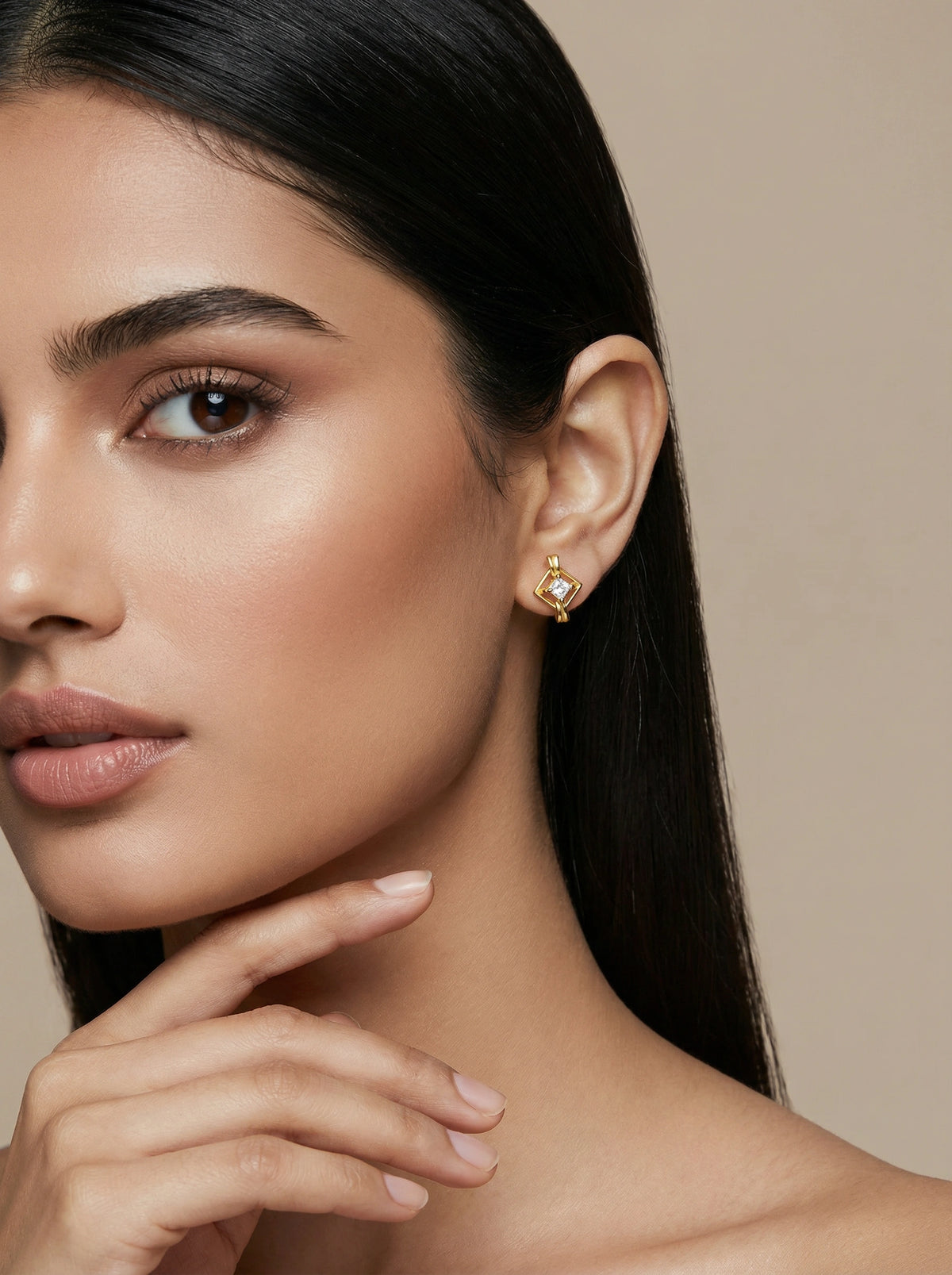 close-up of a woman wearing 18k gold plated earrings with a neutral background