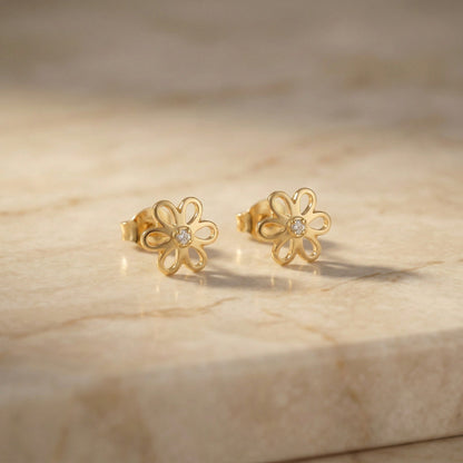 18k Gold plated flower-shaped earrings with diamonds on a beige marble surface