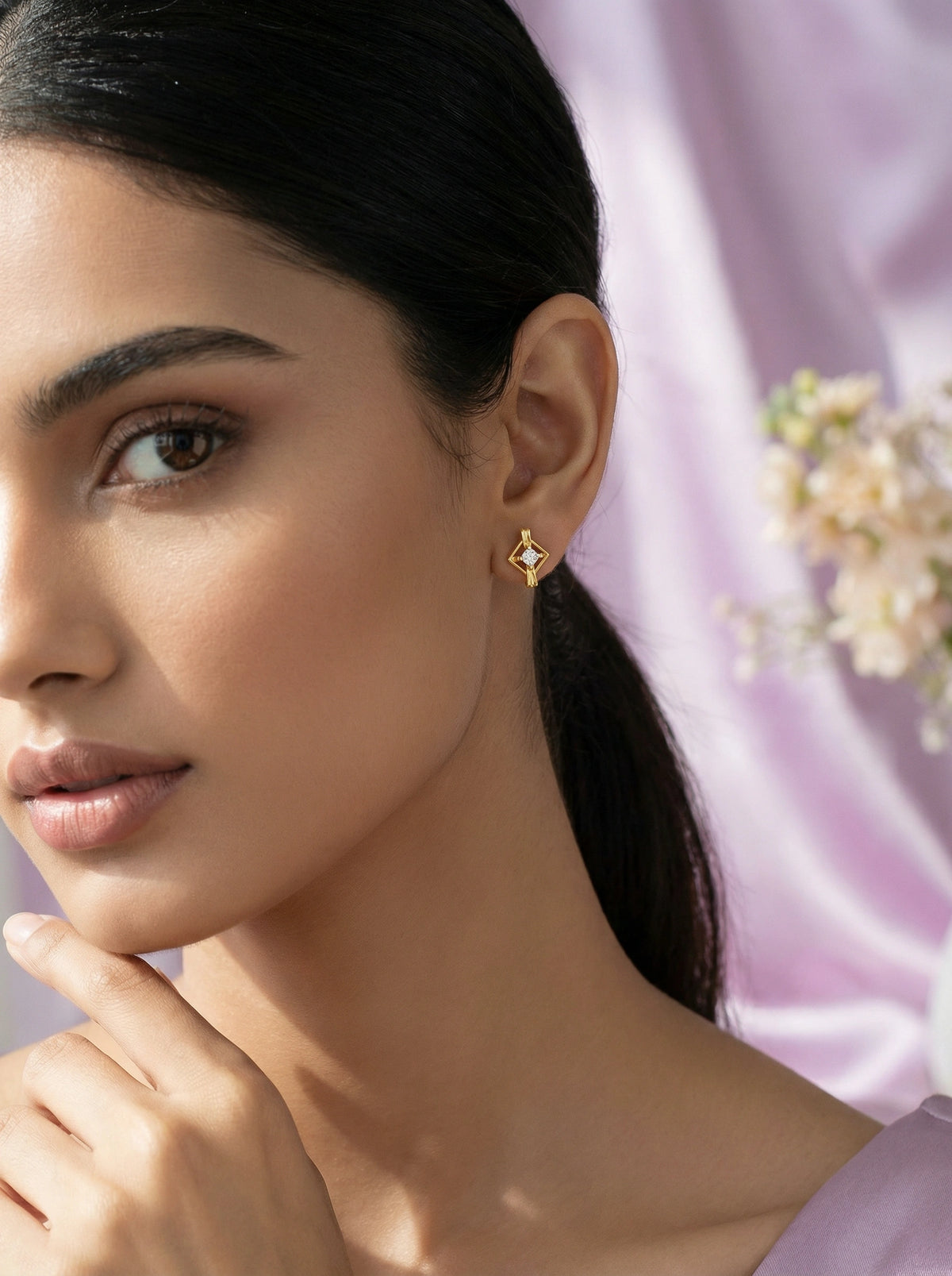 woman wearing a 18k gold plated earring with a blurred floral background