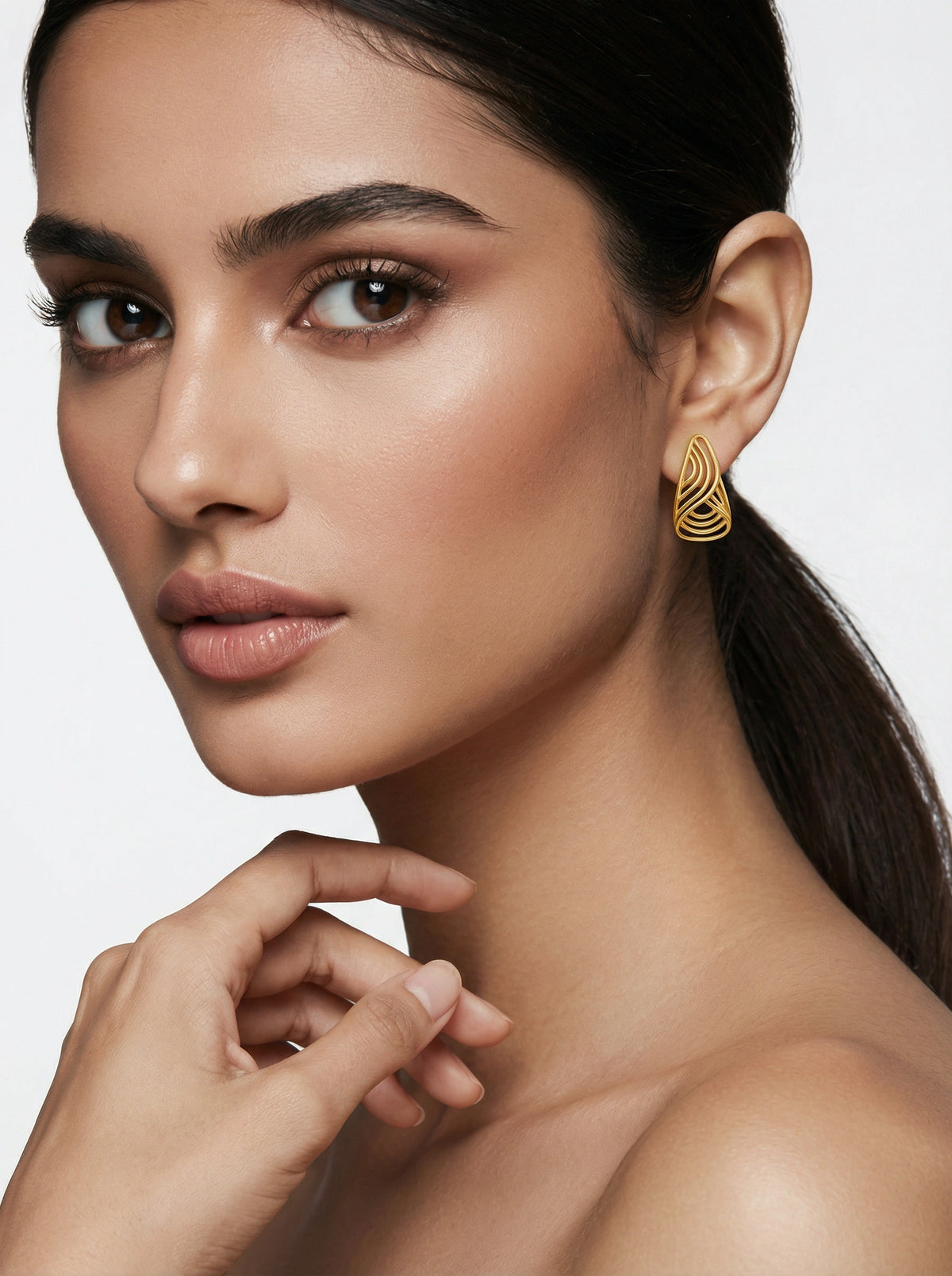 close-up of a woman wearing 18k gold plated earrings with a neutral background
